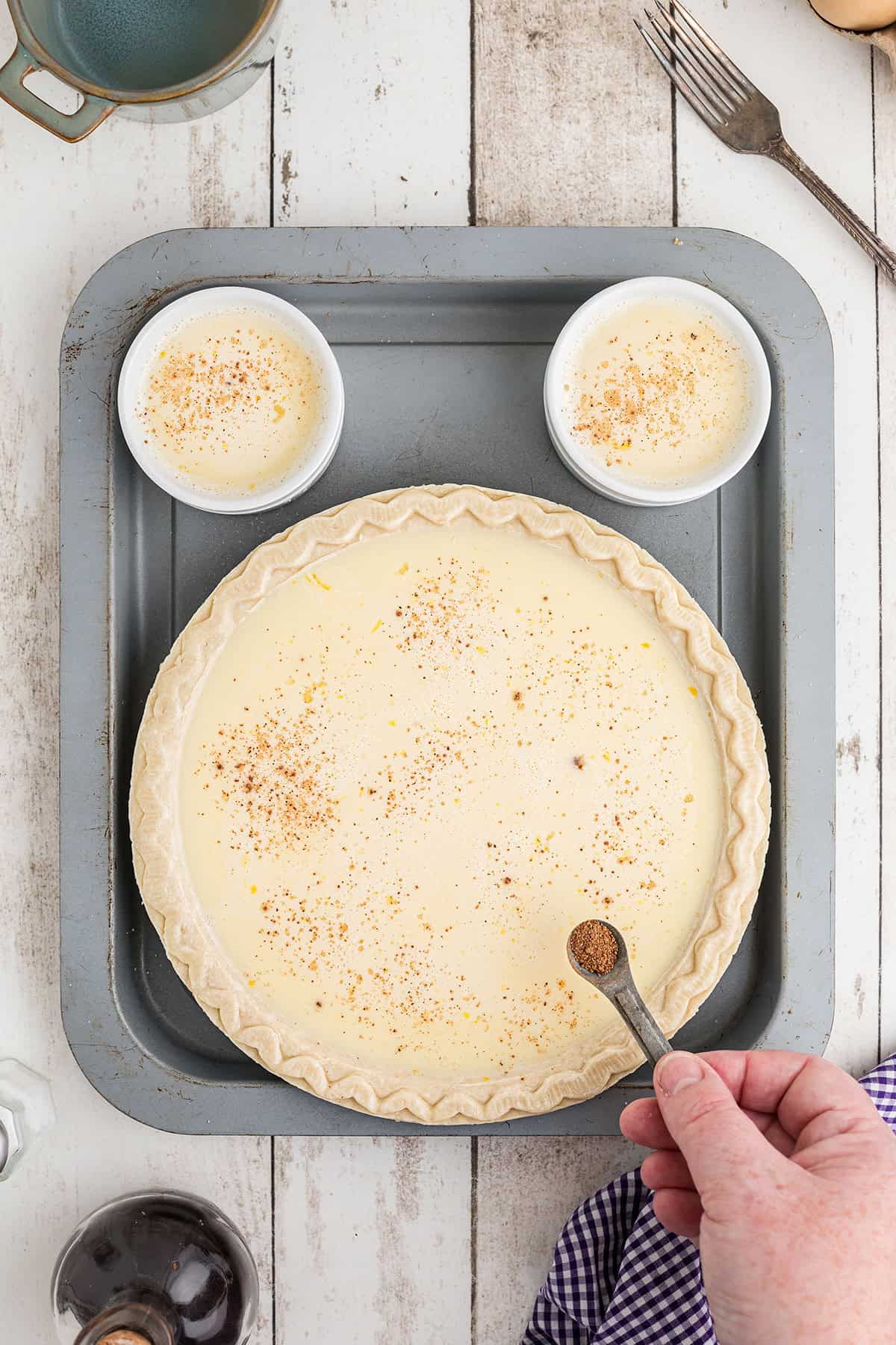 Dusting the top of the custard with nutmeg.
