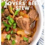 Beef stew with tomatoes, onions, and herbs in a bowl, topped with fresh parsley.