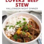 Bowl of beef stew with rice, topped with parsley, on a table with a napkin and spoon nearby.