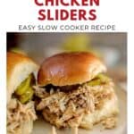 Two shredded chicken sliders with pickles on buns, featured as a slow cooker recipe on a white plate.