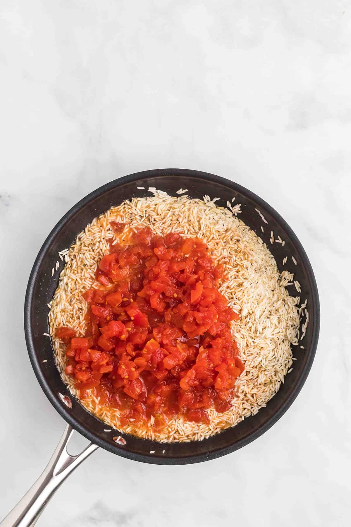 Diced tomatoes added to browned rice.