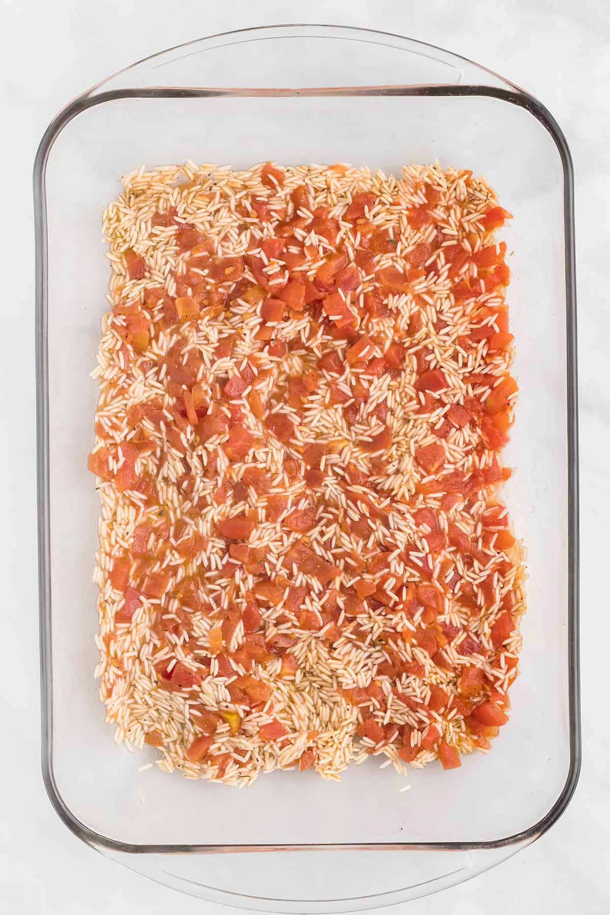 Rice and tomato mixture in a glass baking dish.