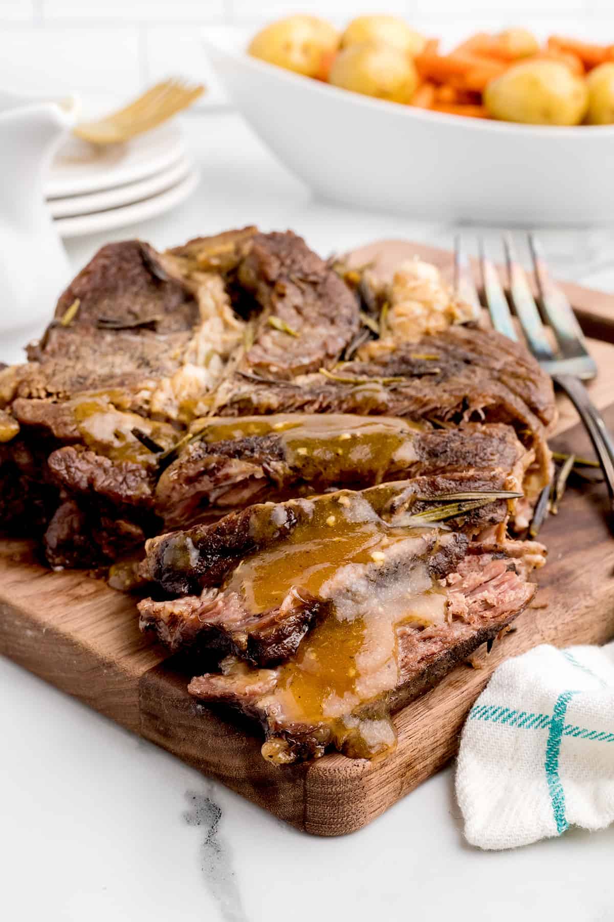 Sliced pot roast on a wooden board.