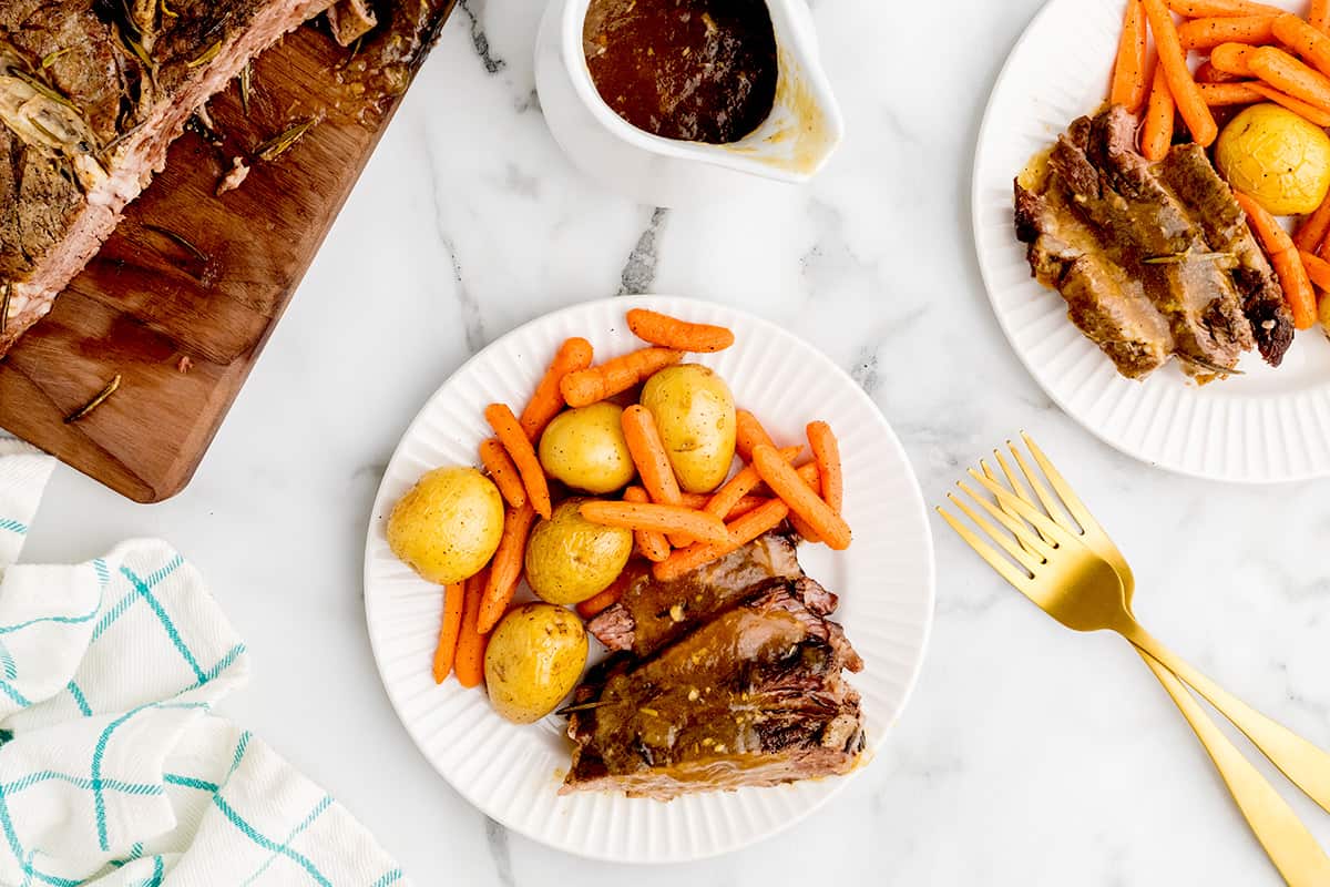 A serving of pot roast with potatoes and carrots on a white plate.