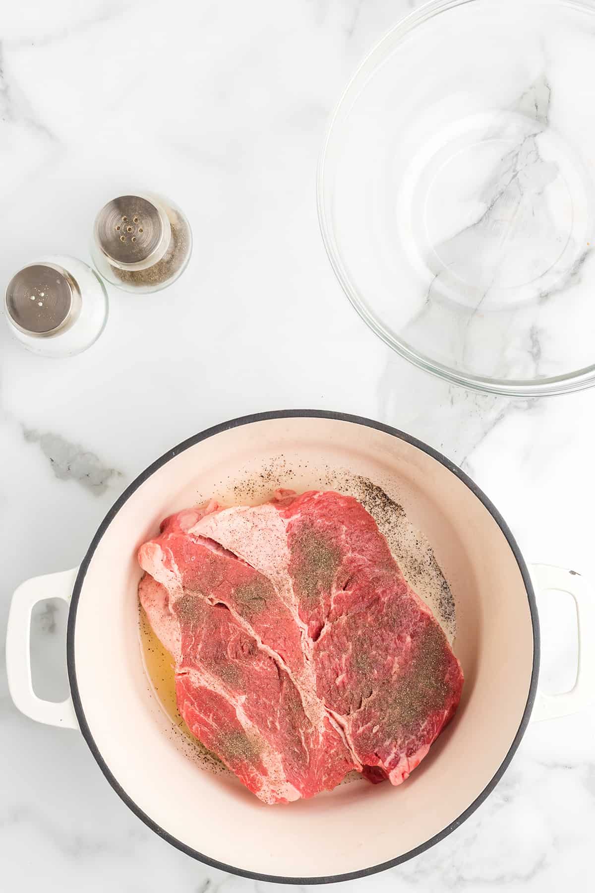 Salt and pepper added to beef roast in a pan.