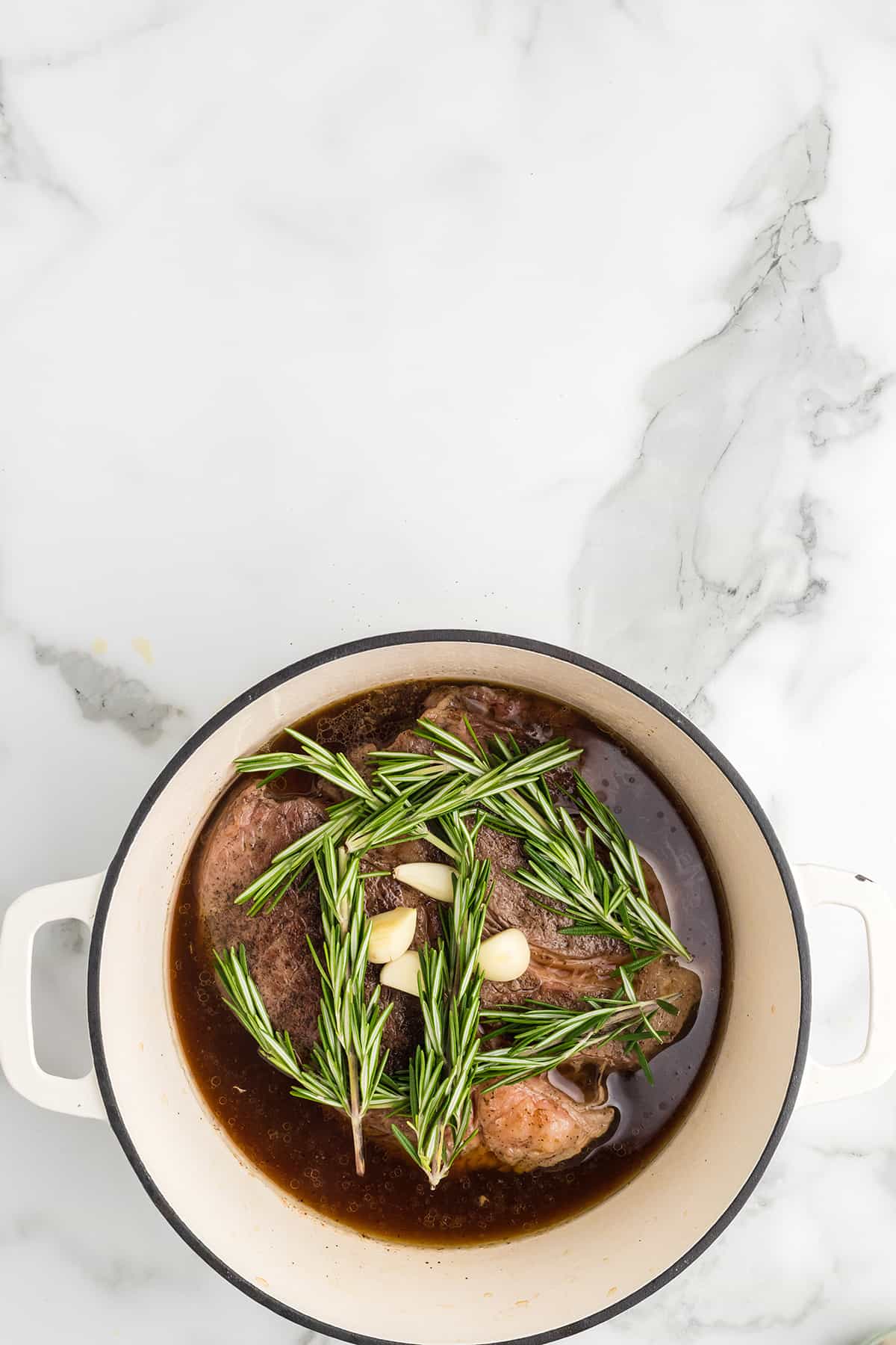 Beef broth, garlic, and rosemary added to the pot.