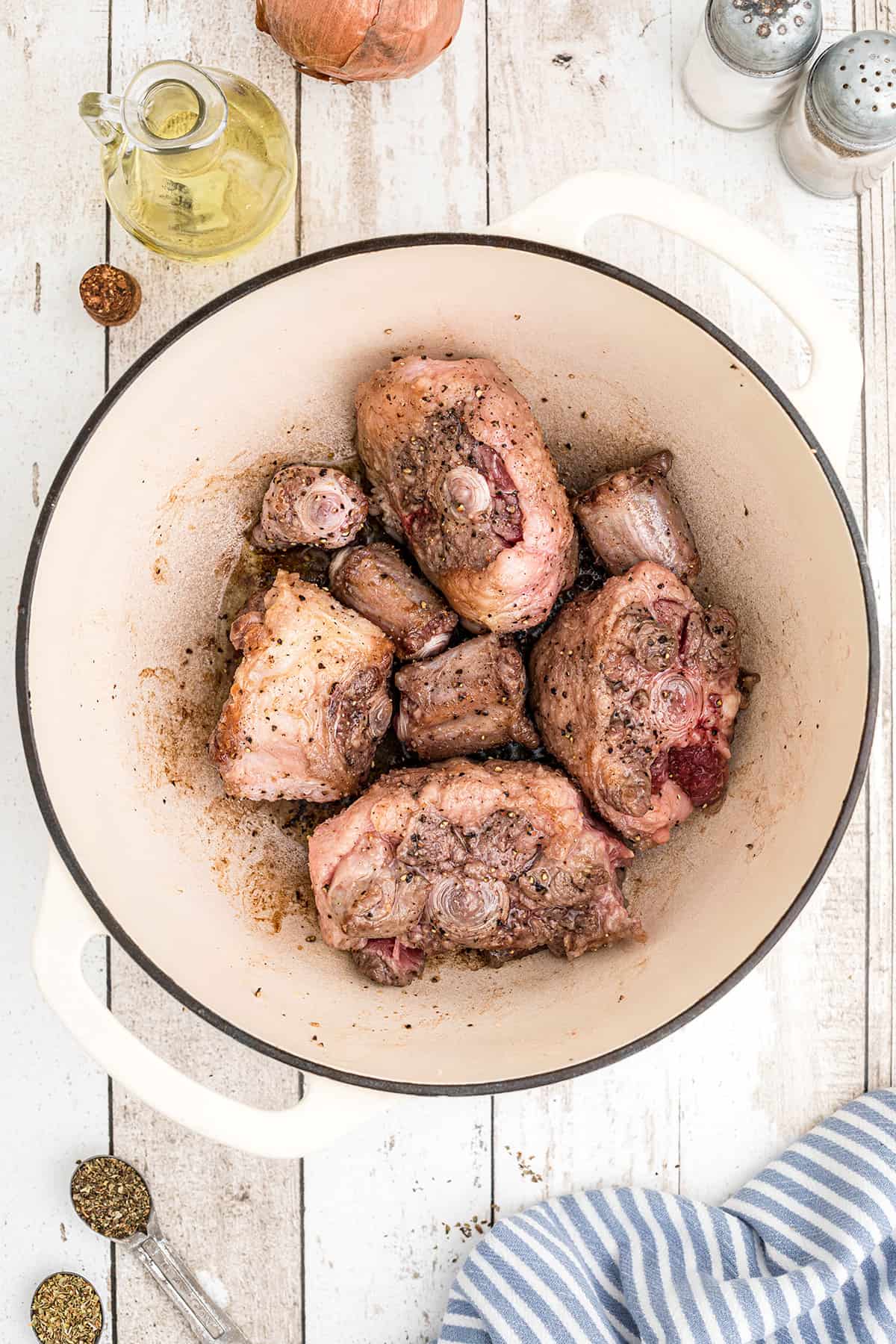 Browned oxtails in a Dutch oven.