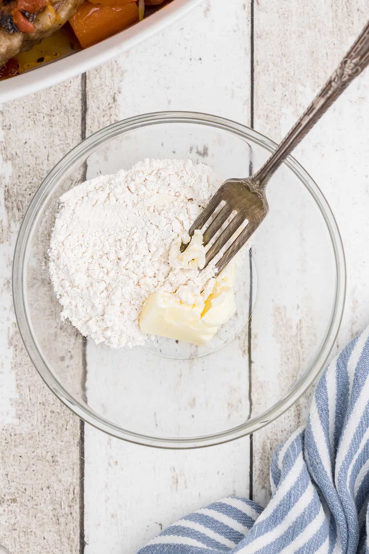 Combining butter and flour with a fork in a small bowl.