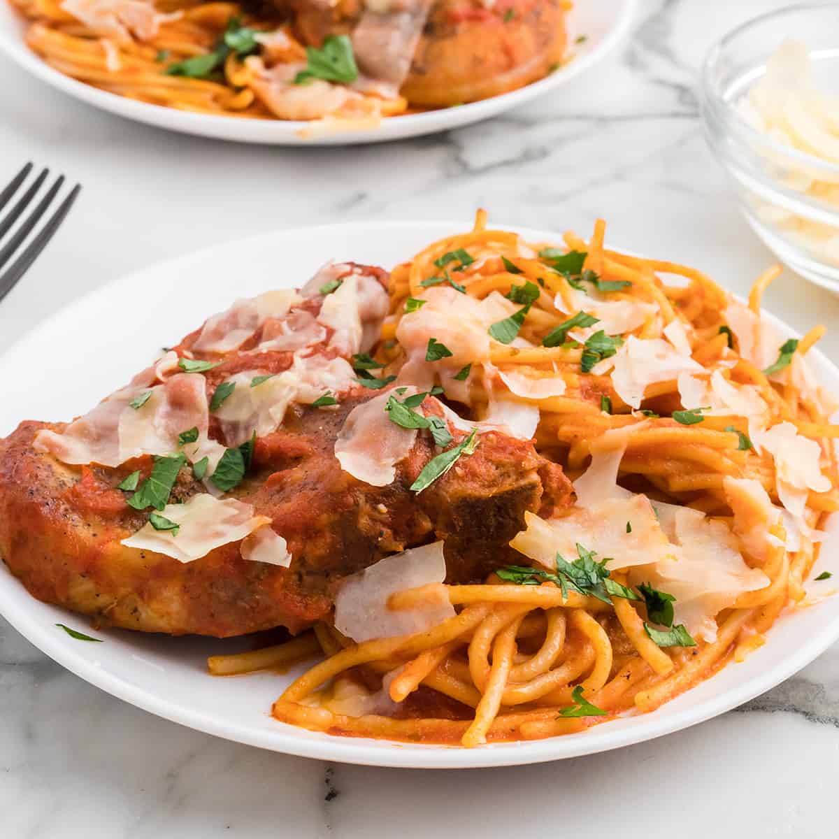 Pork chops and spaghetti on a white plate.