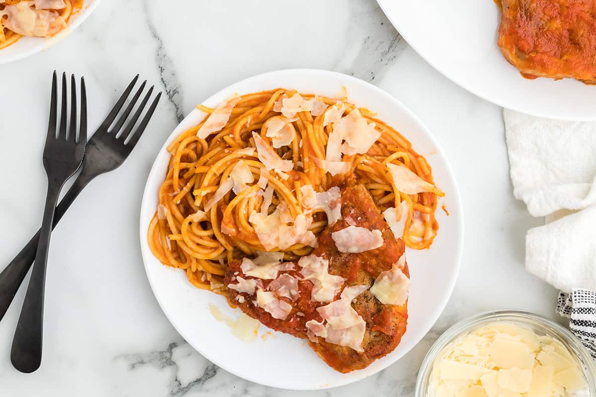 Pork chops and spaghetti on a white plate.