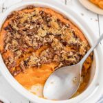 Sweet potato casserole in a white baking dish with a spoon.