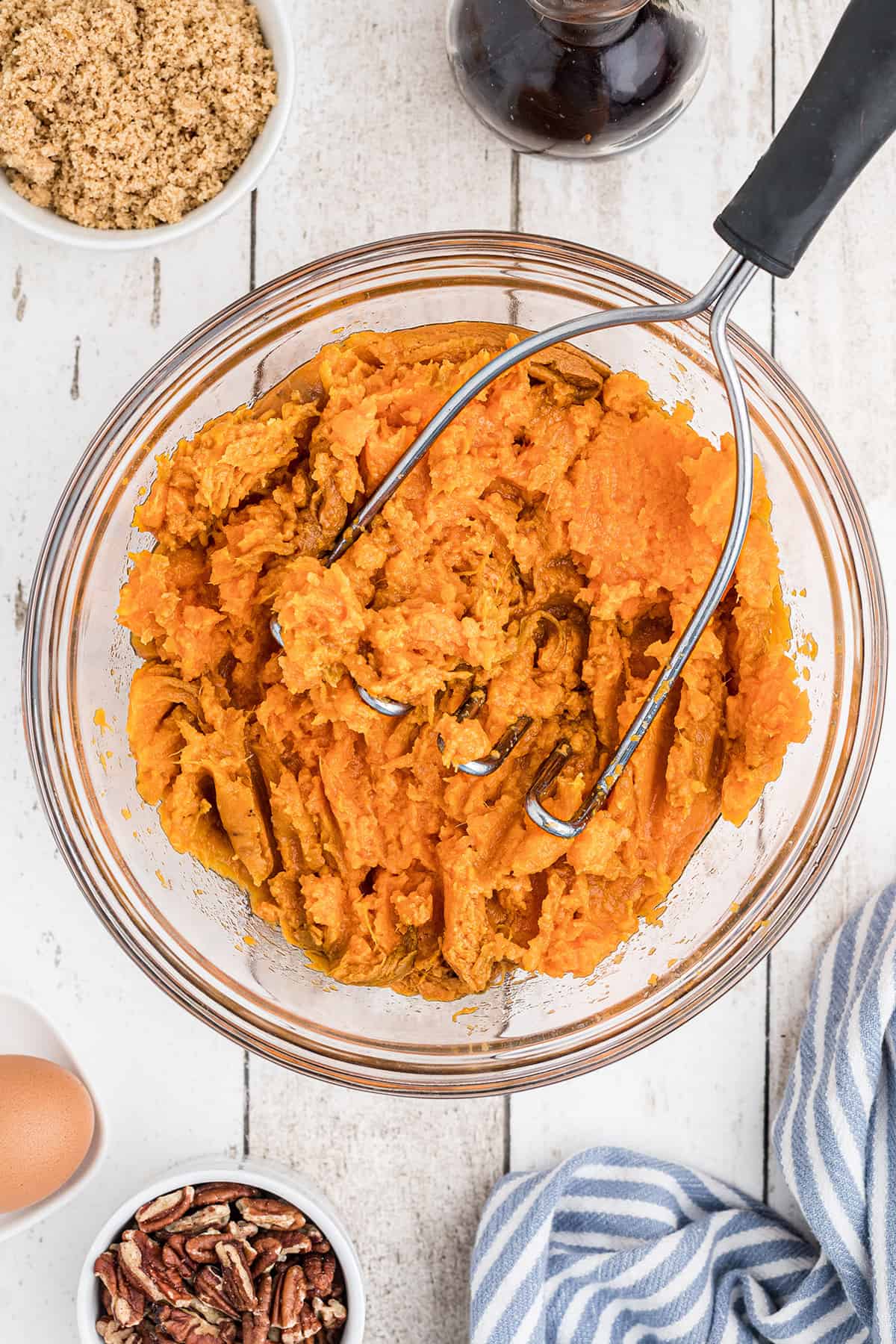 Mashing cooked sweet potatoes in a bowl.