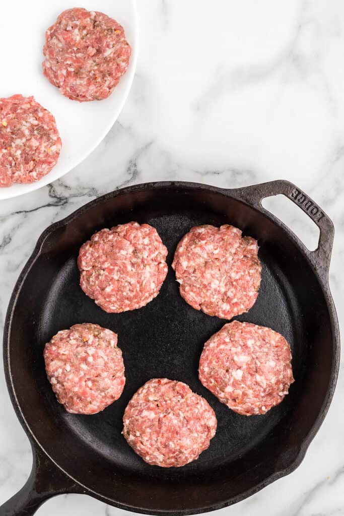 Sausage patties in a cast iron skillet.