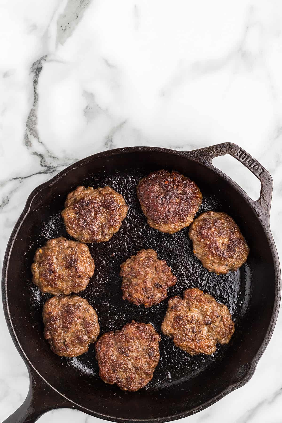Sausage cooking on the second side in a skillet.