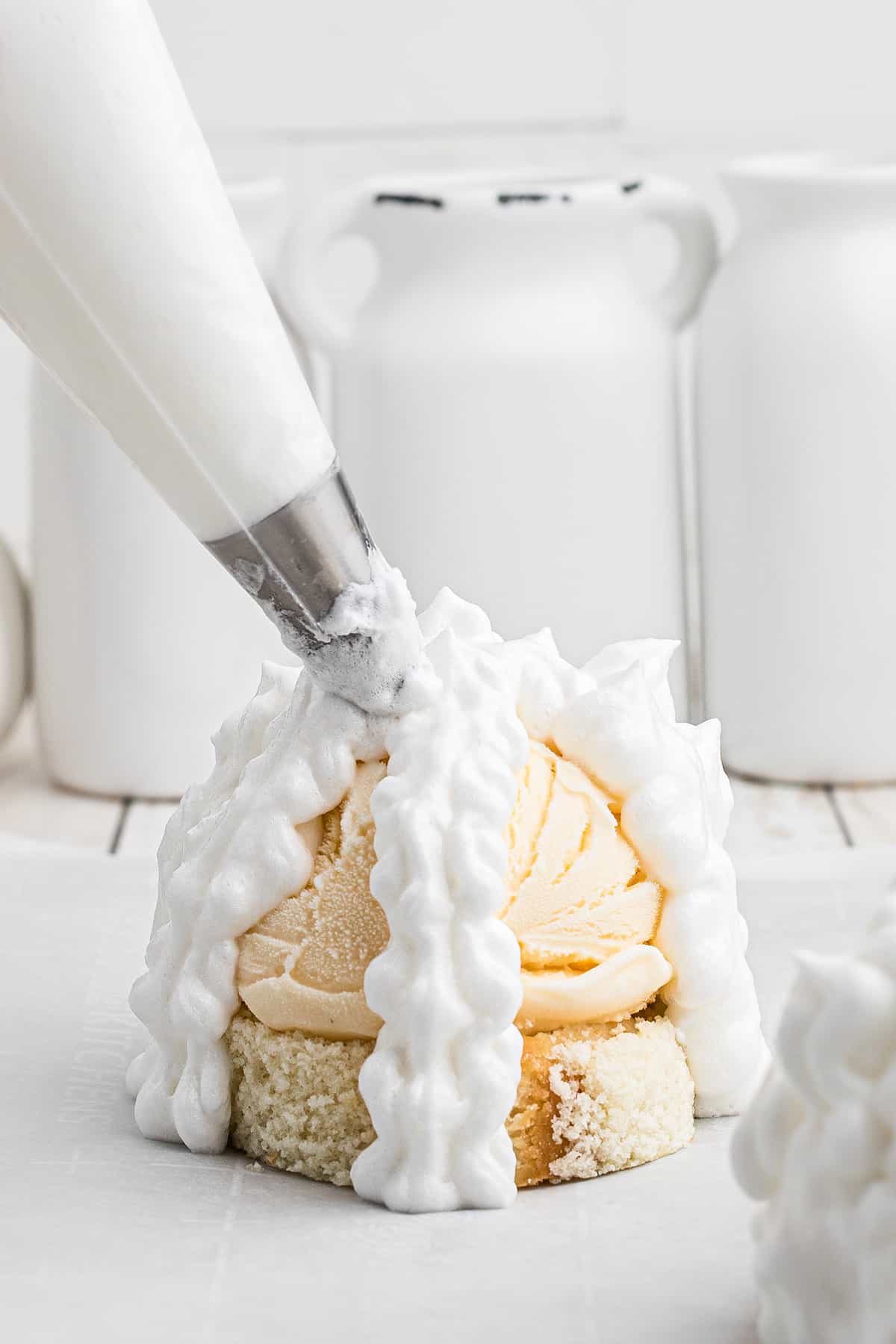 Piping meringue over the ice cream and cake.