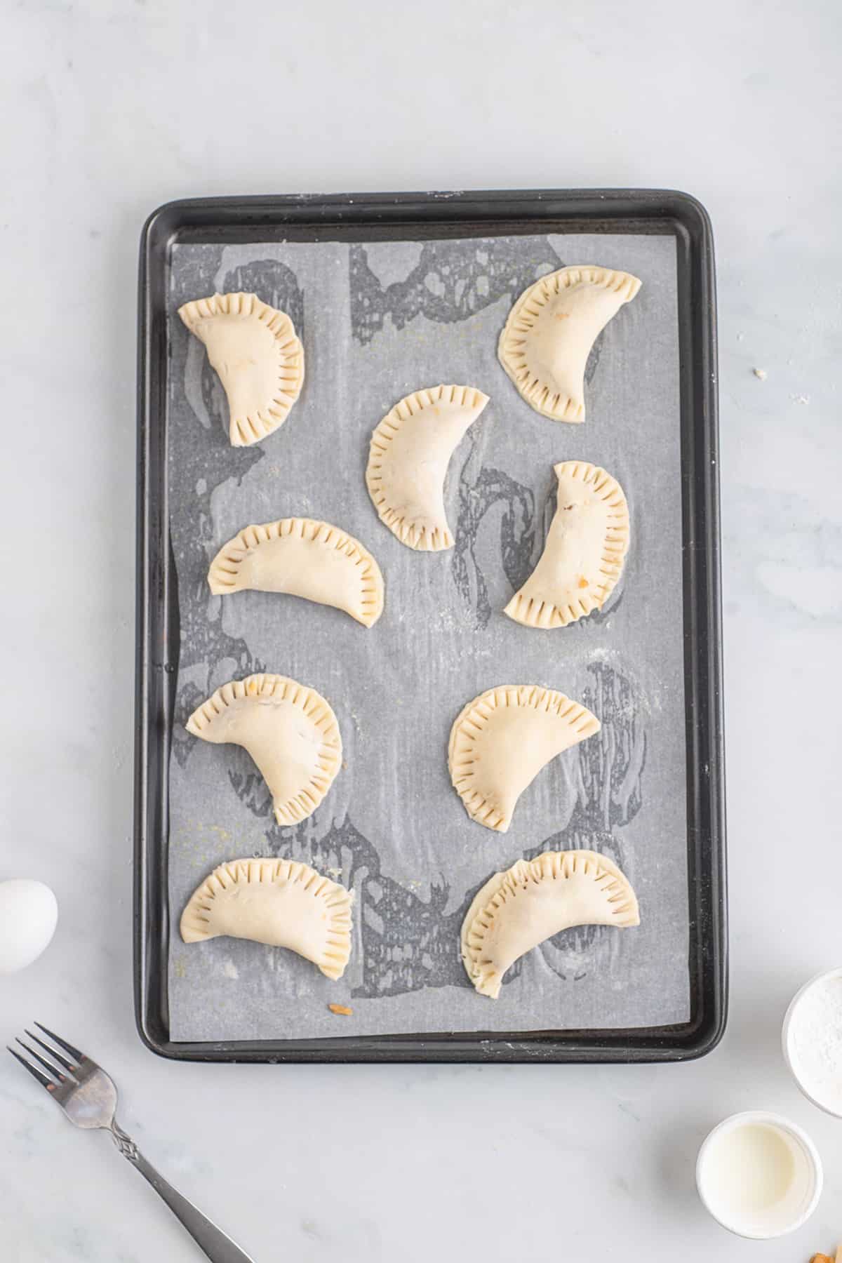 Pies placed on a parchment lined baking sheet.