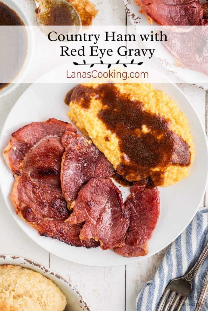 A plate filled with country ham, cheese grits, and red eye gravy.