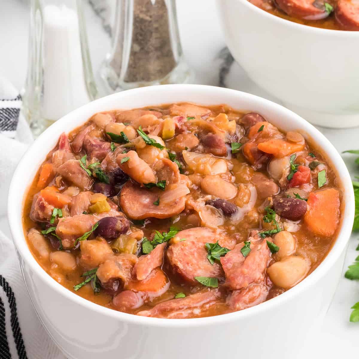 A serving of mixed bean soup in a white bowl.