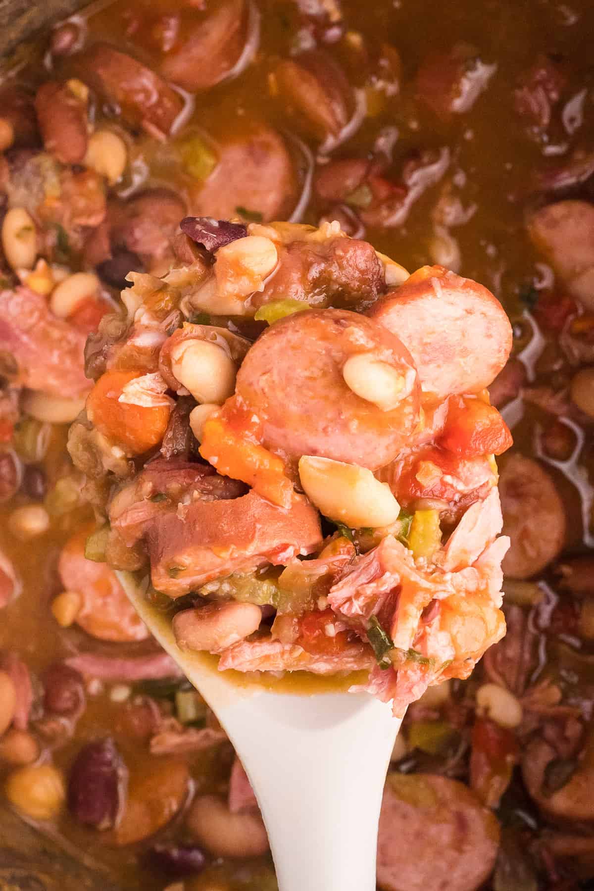 A wooden spoon filled with mixed bean soup.