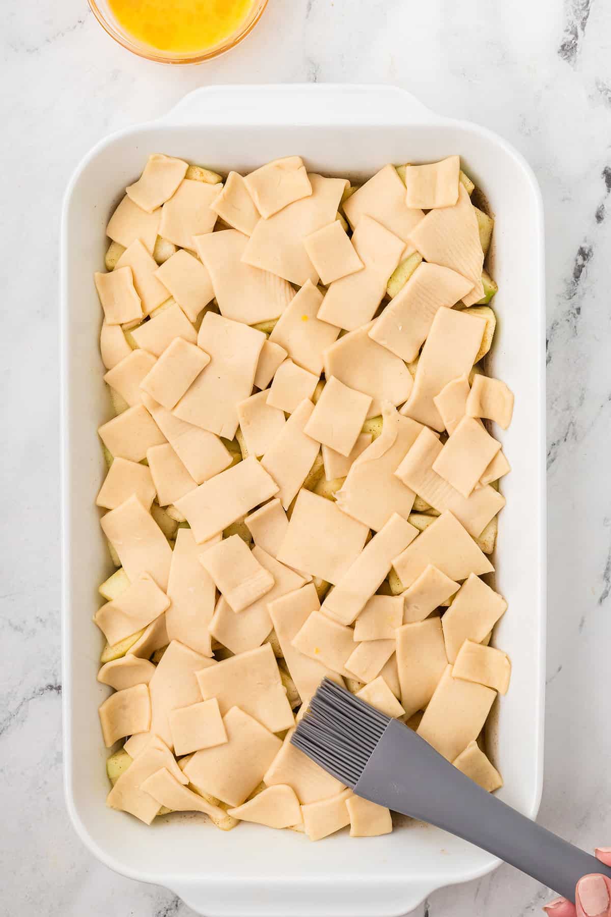 Applying egg wash to the top of the crust.