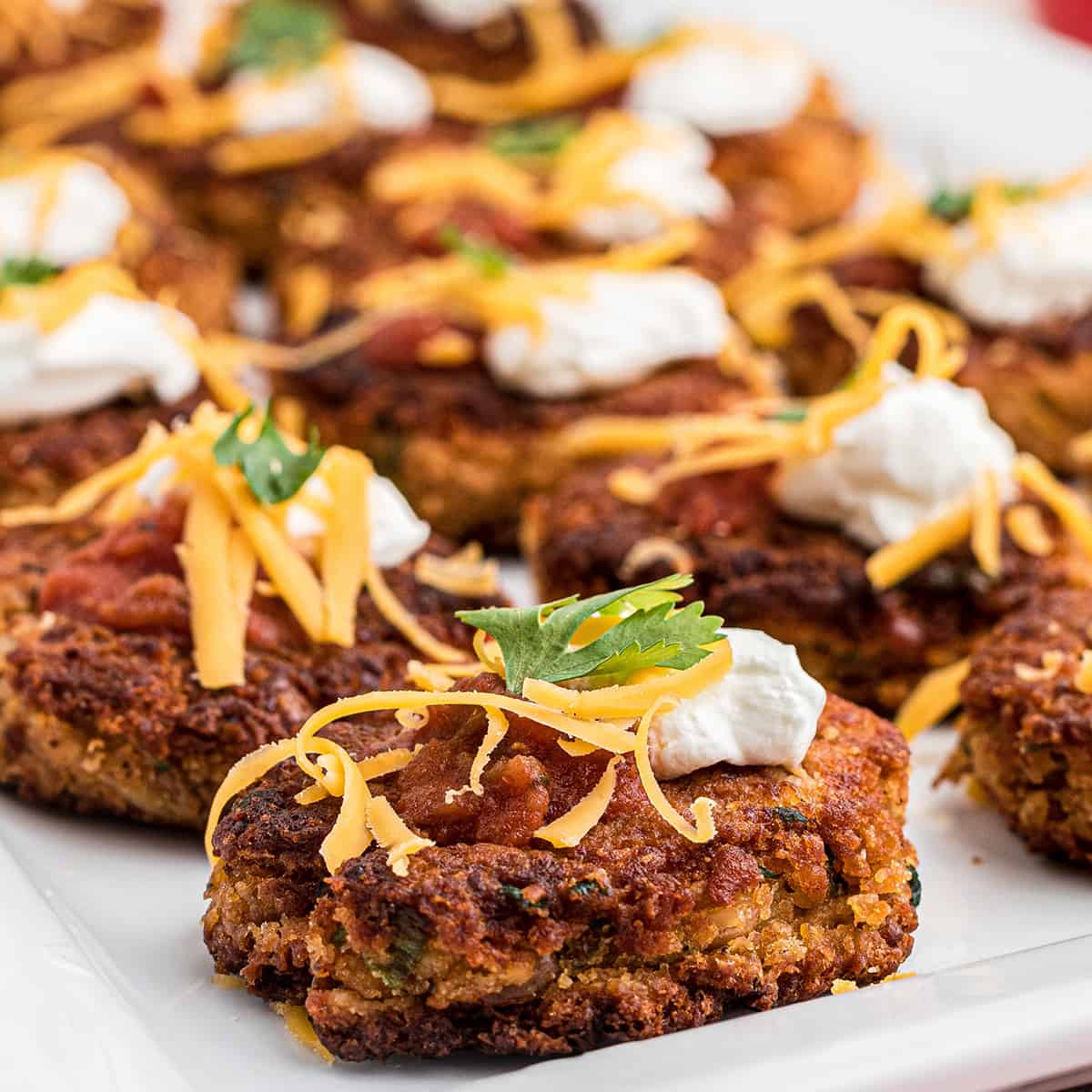 Finished pinto bean cakes on a white serving plate.