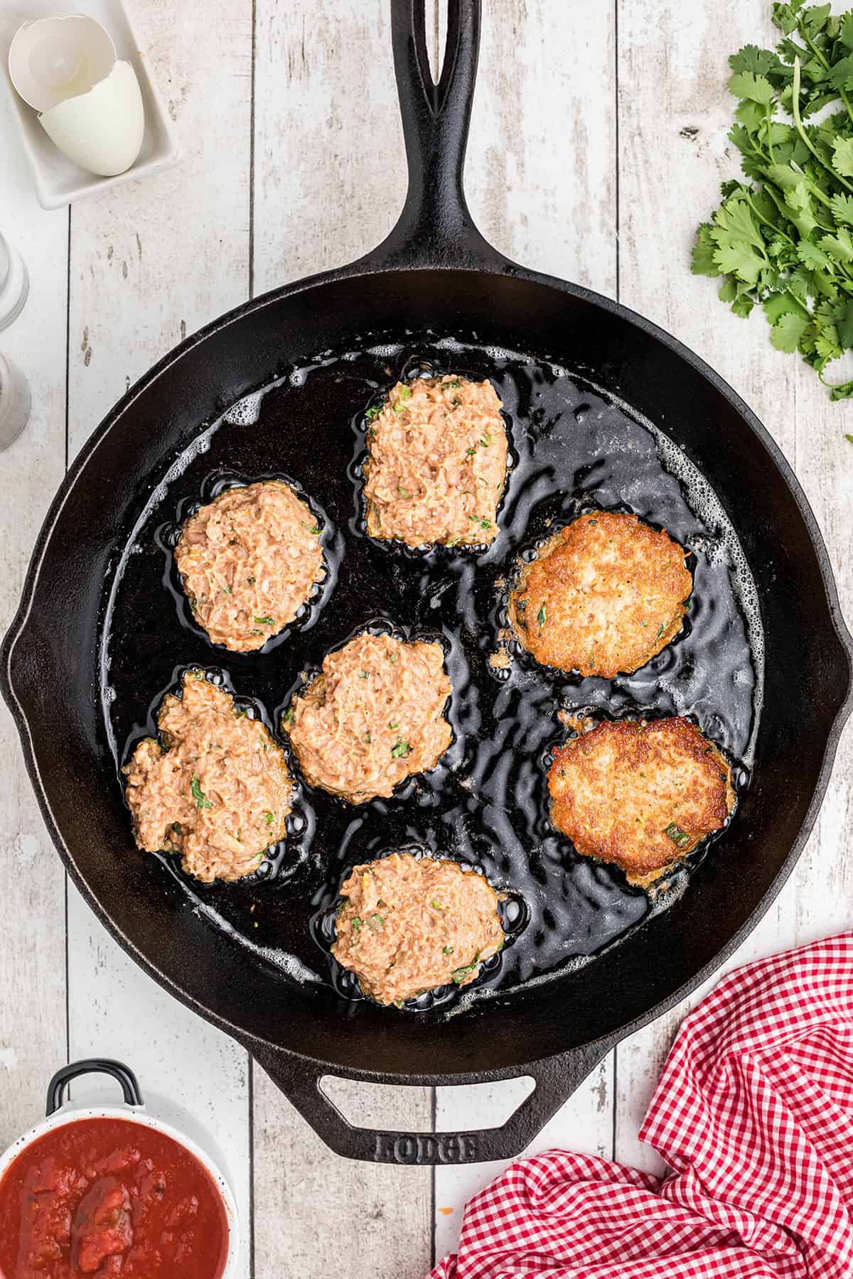 Bean patties frying in an iron skillet.