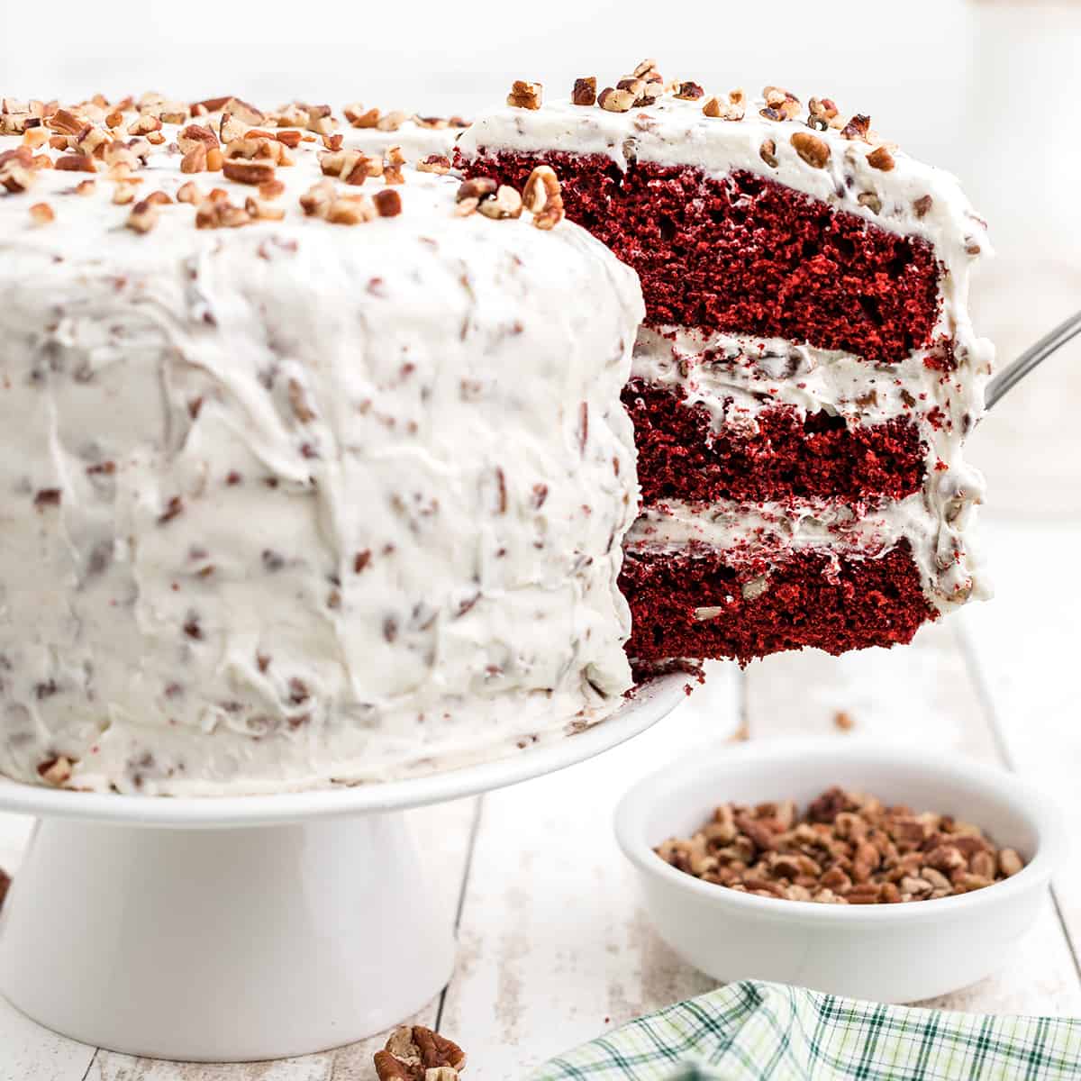 Finished red velvet cake with a slice held on a cake server.