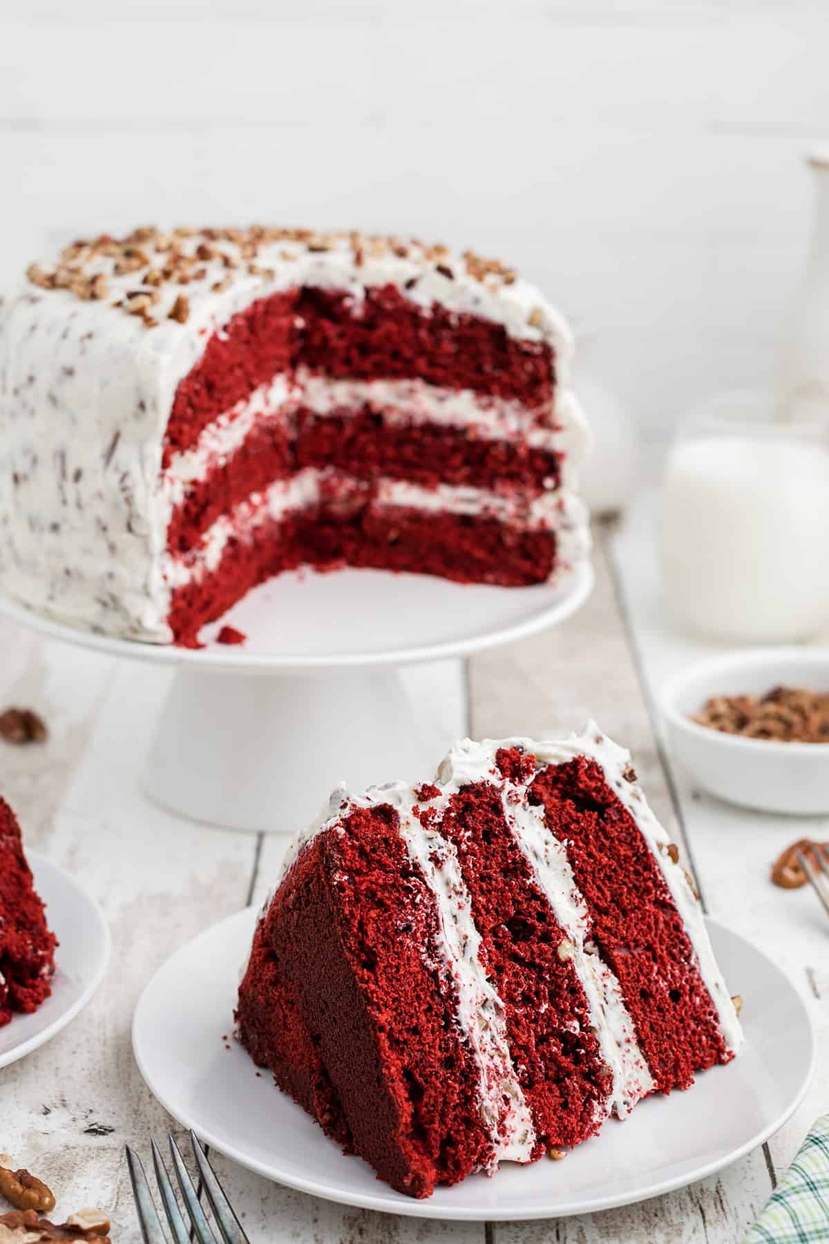 Finished red velvet cake with a slice held on a plate.