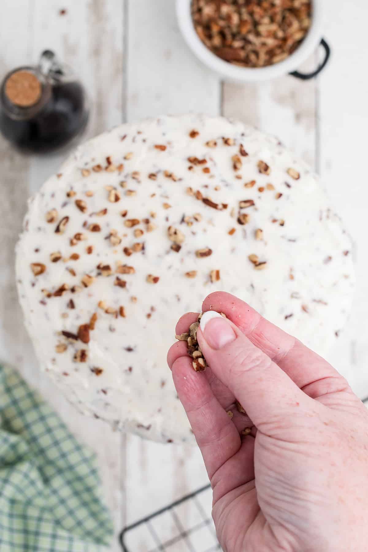 Garnishing top of the cake with chopped pecans.