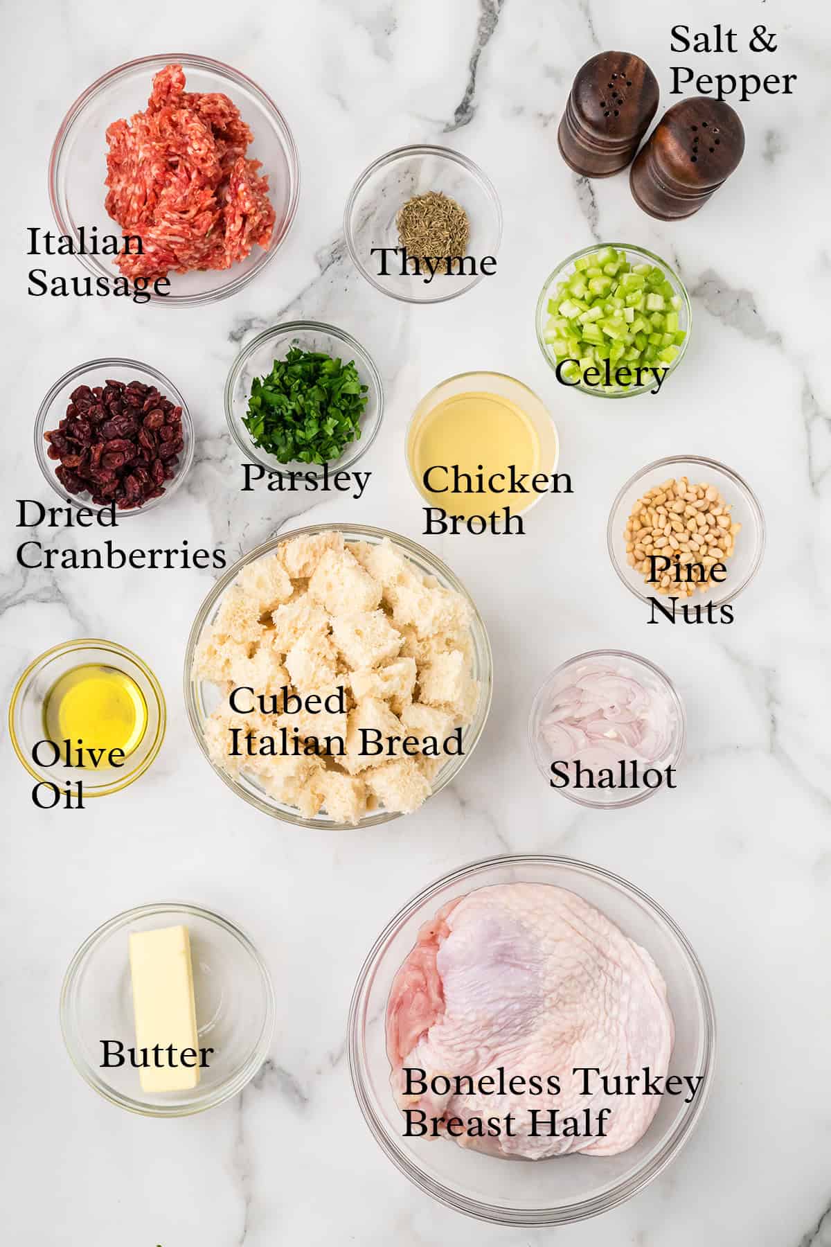 Ingredients for turkey roulade, including sausage, bread, herbs, broth, cranberries, nuts, butter, and turkey.