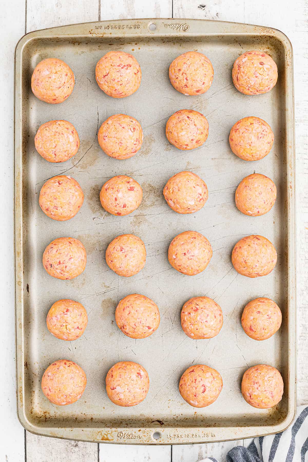 Sausage balls on a cookie sheet ready to bake.