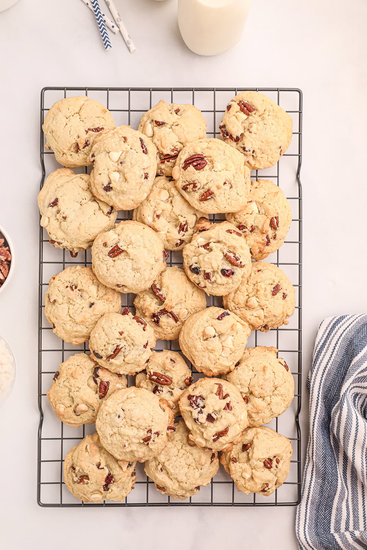 A cooling rack filled with freshly baked pecan cookies on a light surface.