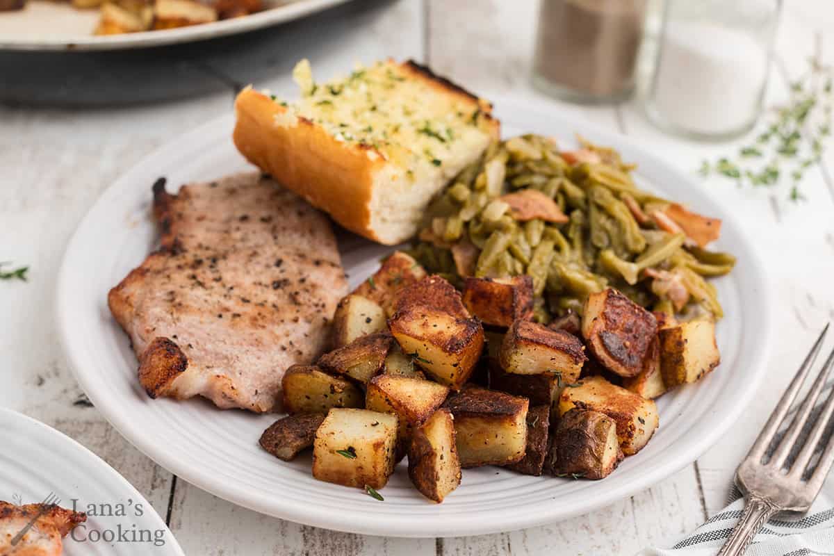Home fries on a plate with green beans and ham.
