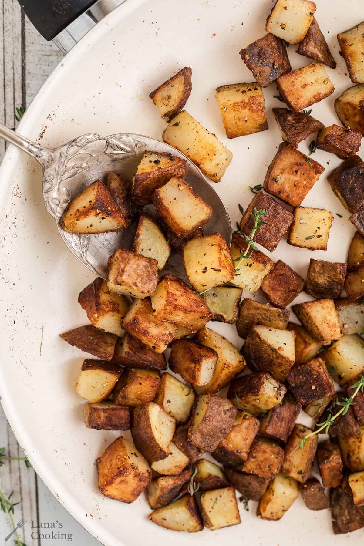 Finished home fries in a white skillet.