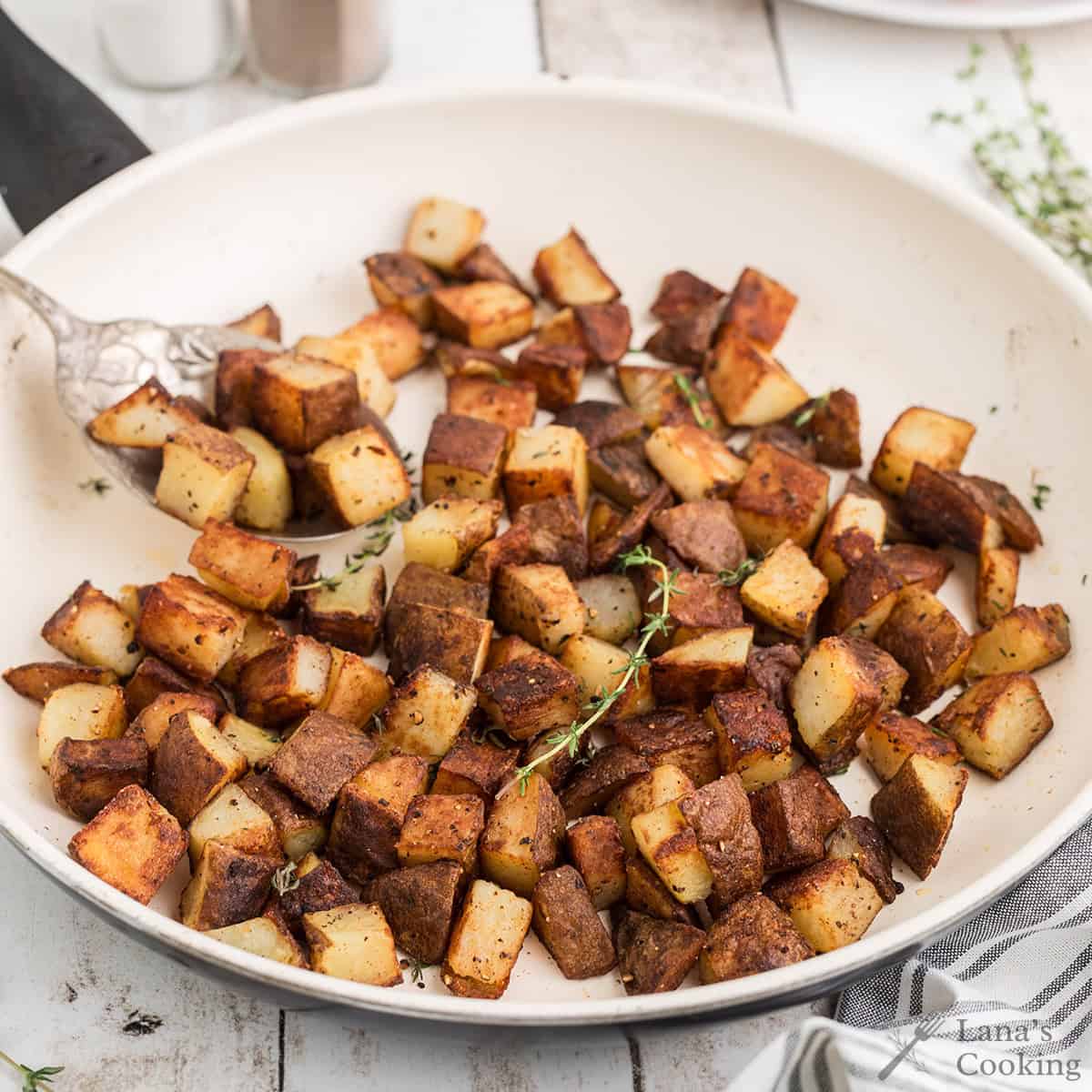 Finished home fries in a skillet.
