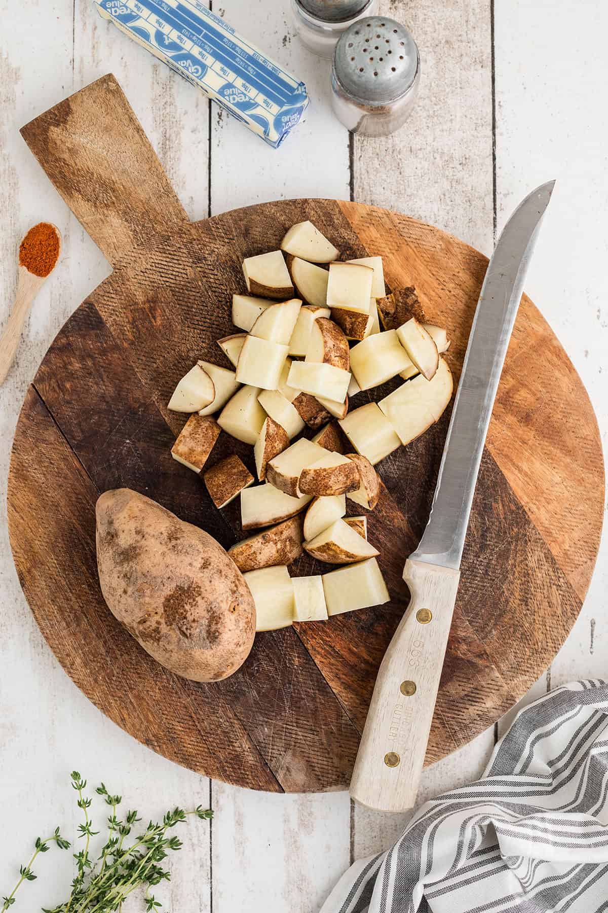 Cut potatoes and a knife on a wooden board.