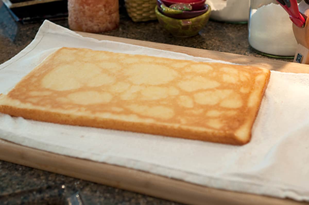 Hot baked cake inverted onto the sugar sprinkled tea towel.