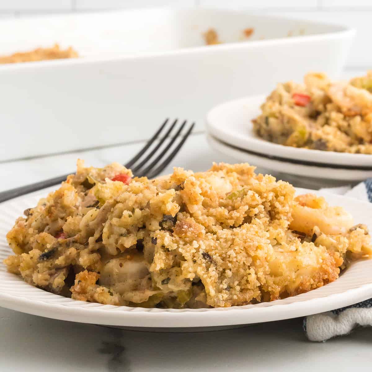 A serving of seafood casserole on a white plate with a fork on the side.