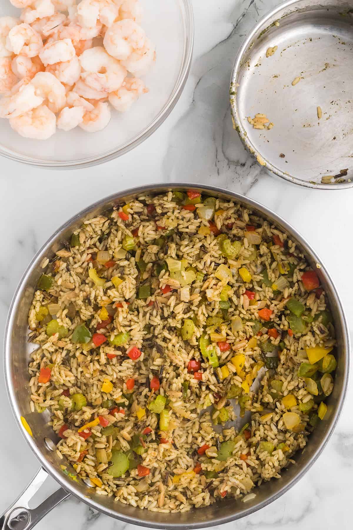 Rice mixture added to the vegetables in a skillet.