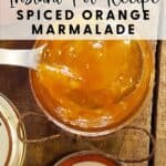Open jar of orange marmalade with a spoon, labeled Instant Pot Recipe Spiced Orange Marmalade on rustic wood.