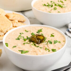 A bowl of white chicken chili garnished with jalapeno slices and cilantro,