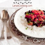 A serving of black beans and rice with ham on a dinner plate.