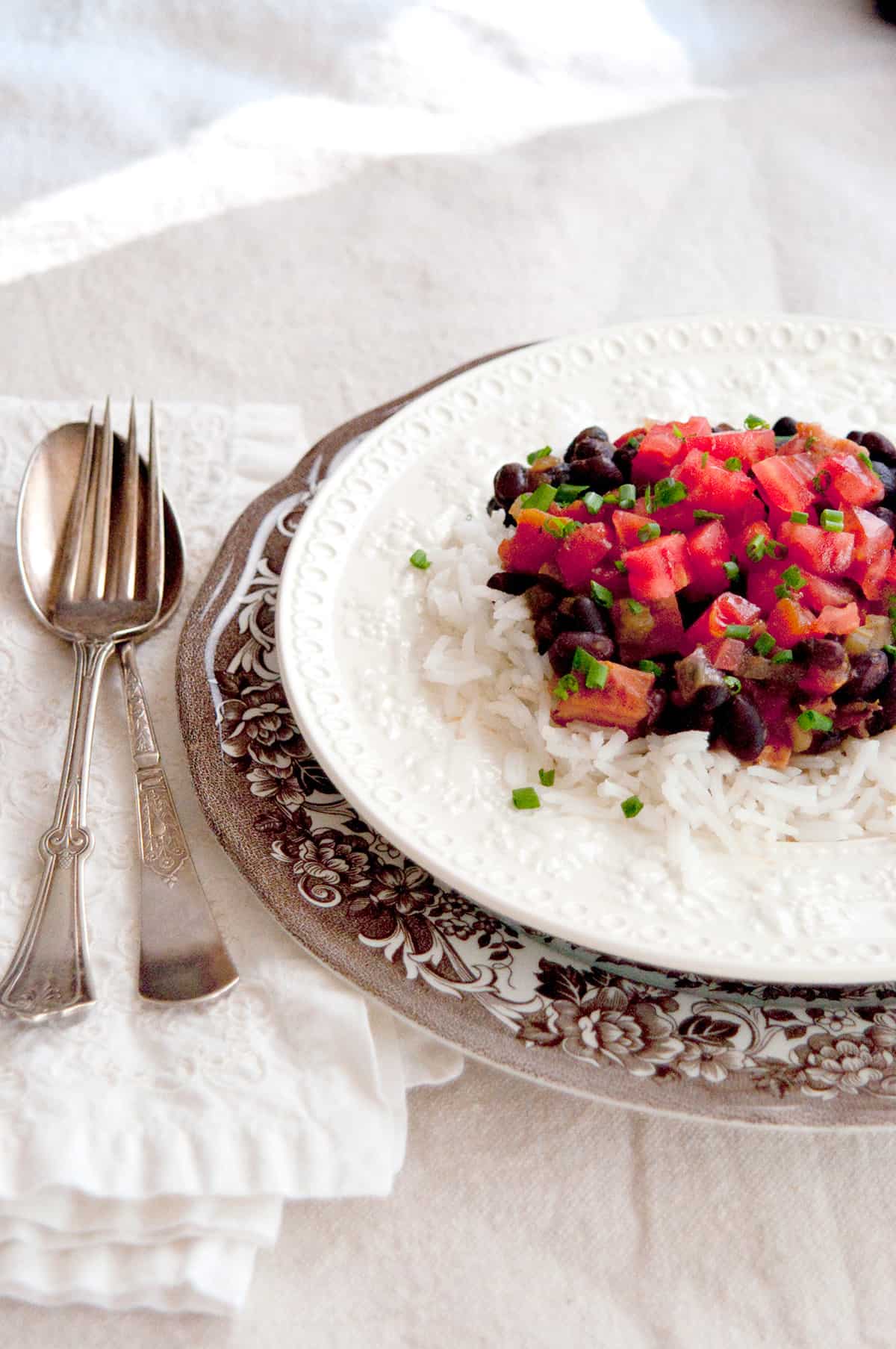 A serving of black beans and rice with ham on a dinner plate.