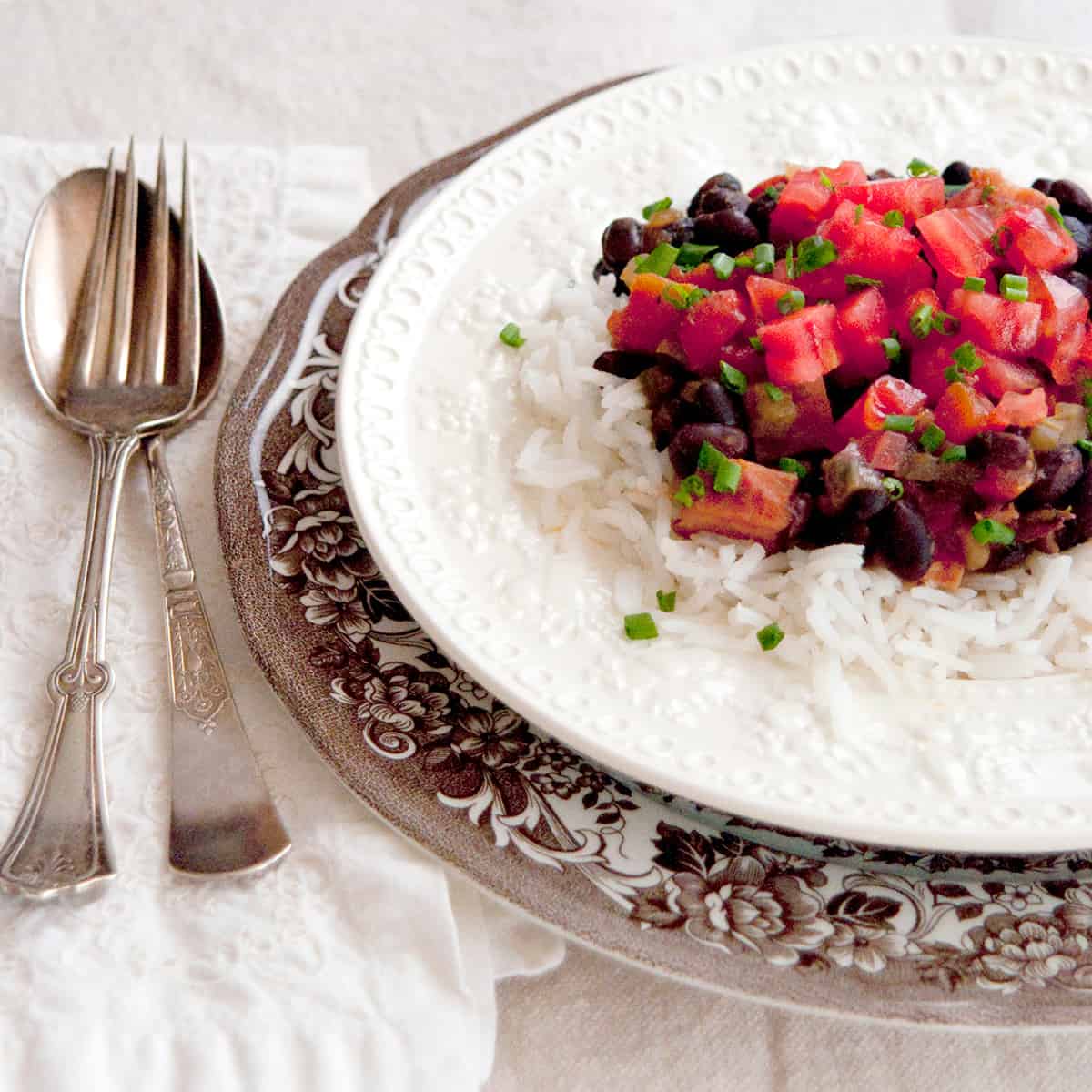 A serving of black beans and rice with ham on a dinner plate.