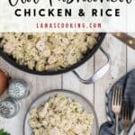 A skillet and plate of old fashioned chicken and rice, with utensils and garnishes on a rustic wooden table.