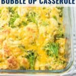 A baked chicken and broccoli casserole topped with melted cheese in a clear glass dish.
