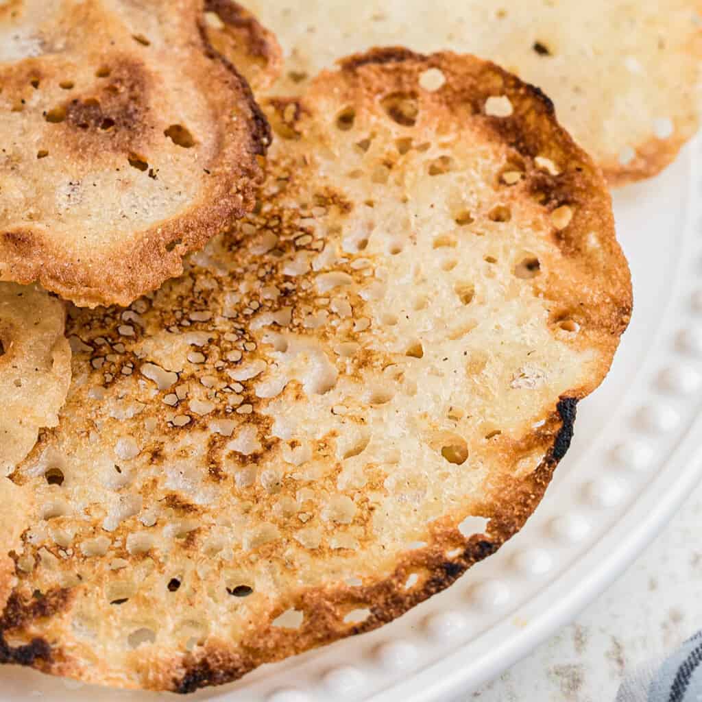 A stack of lacy cornbread on a white plate.