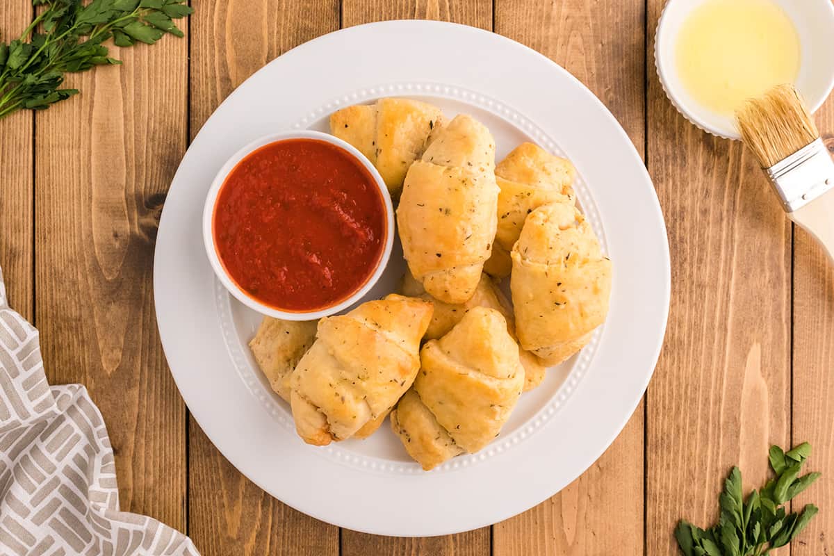 Pizza rolls on a plate with a dish of pizza sauce.