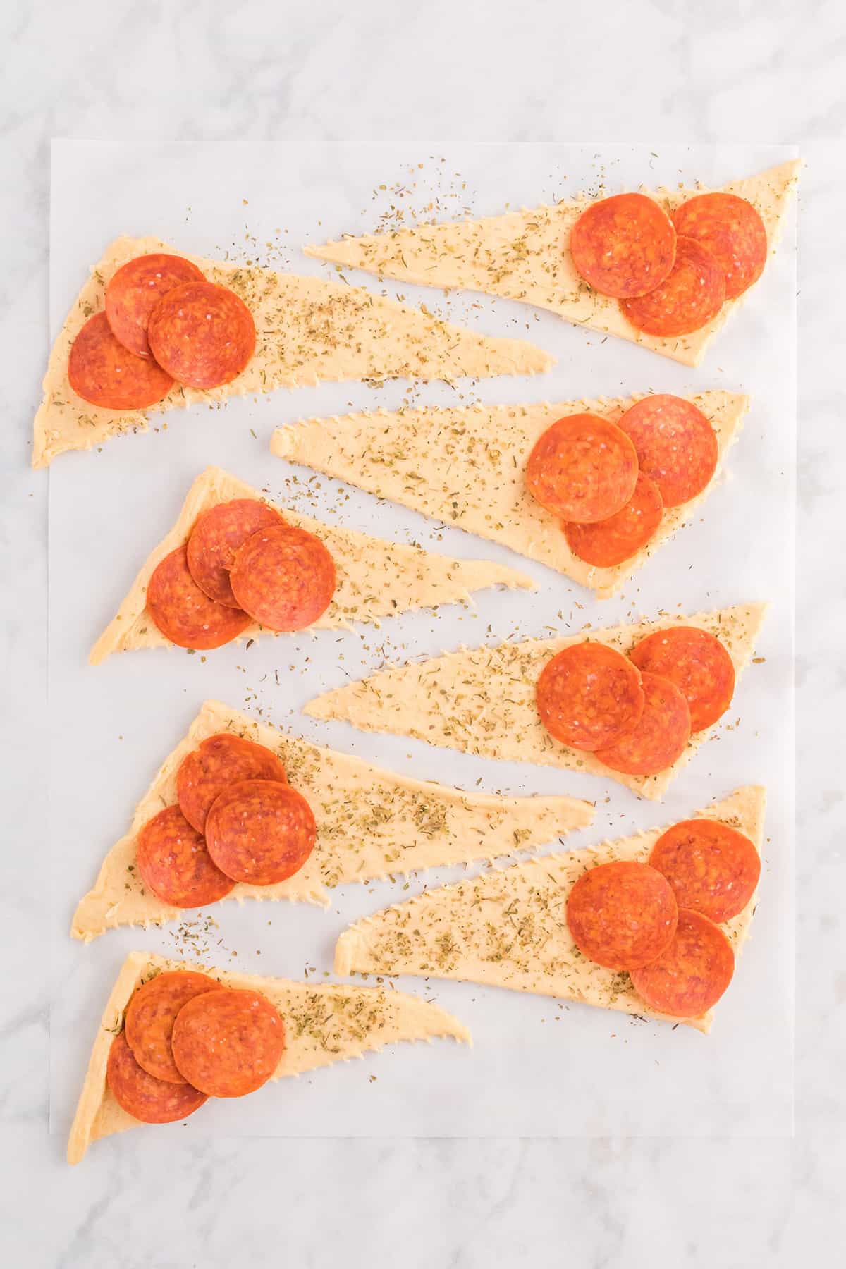 Pepperoni added to each dough triangle.