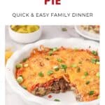 A cheeseburger pie in a white dish, topped with melted cheese and green onions, with a slice missing.
